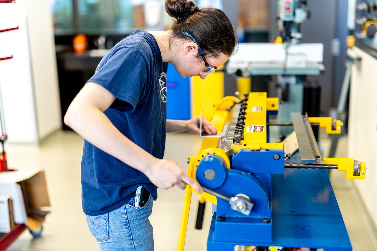 Student using a metal press machine in the Gina Cody School Makerspace lab.