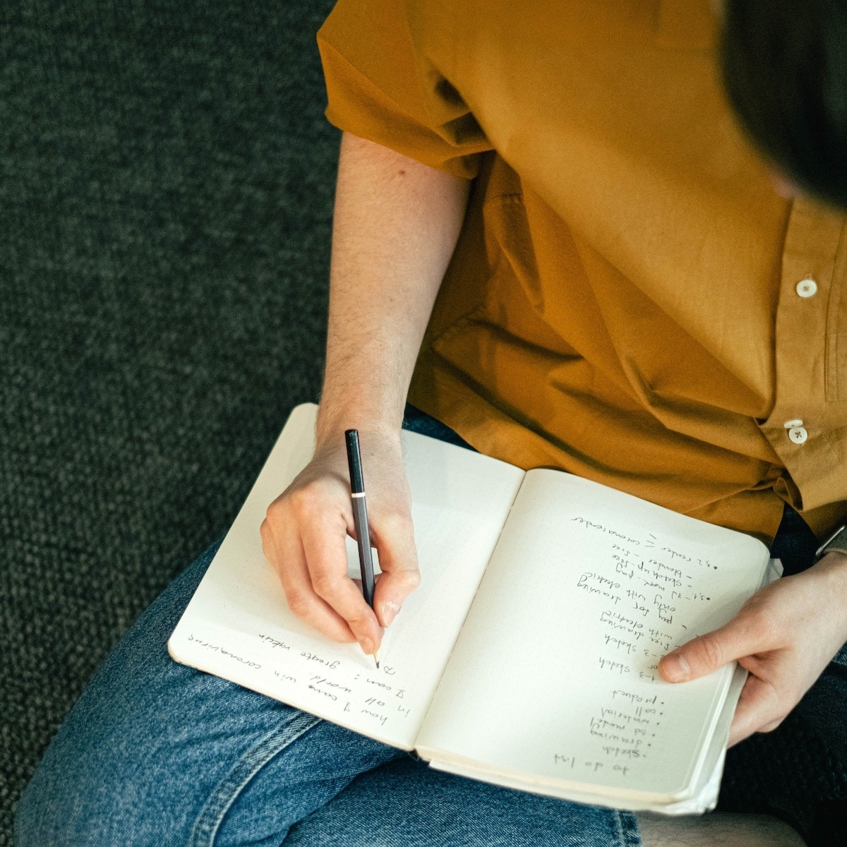 A seated man writes in a journal